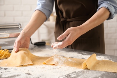 Young woman preparing dough for pasta at table