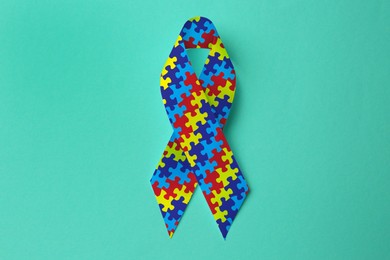 Image of World Autism Awareness Day. Colorful puzzle ribbon on cyan background, top view