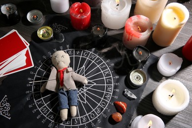 Voodoo doll pierced with needle surrounded by ceremonial items on table. Curse ceremony