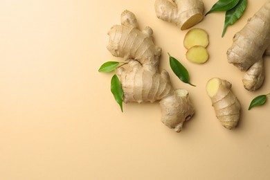Photo of Fresh ginger with green leaves on beige background, flat lay. Space for text
