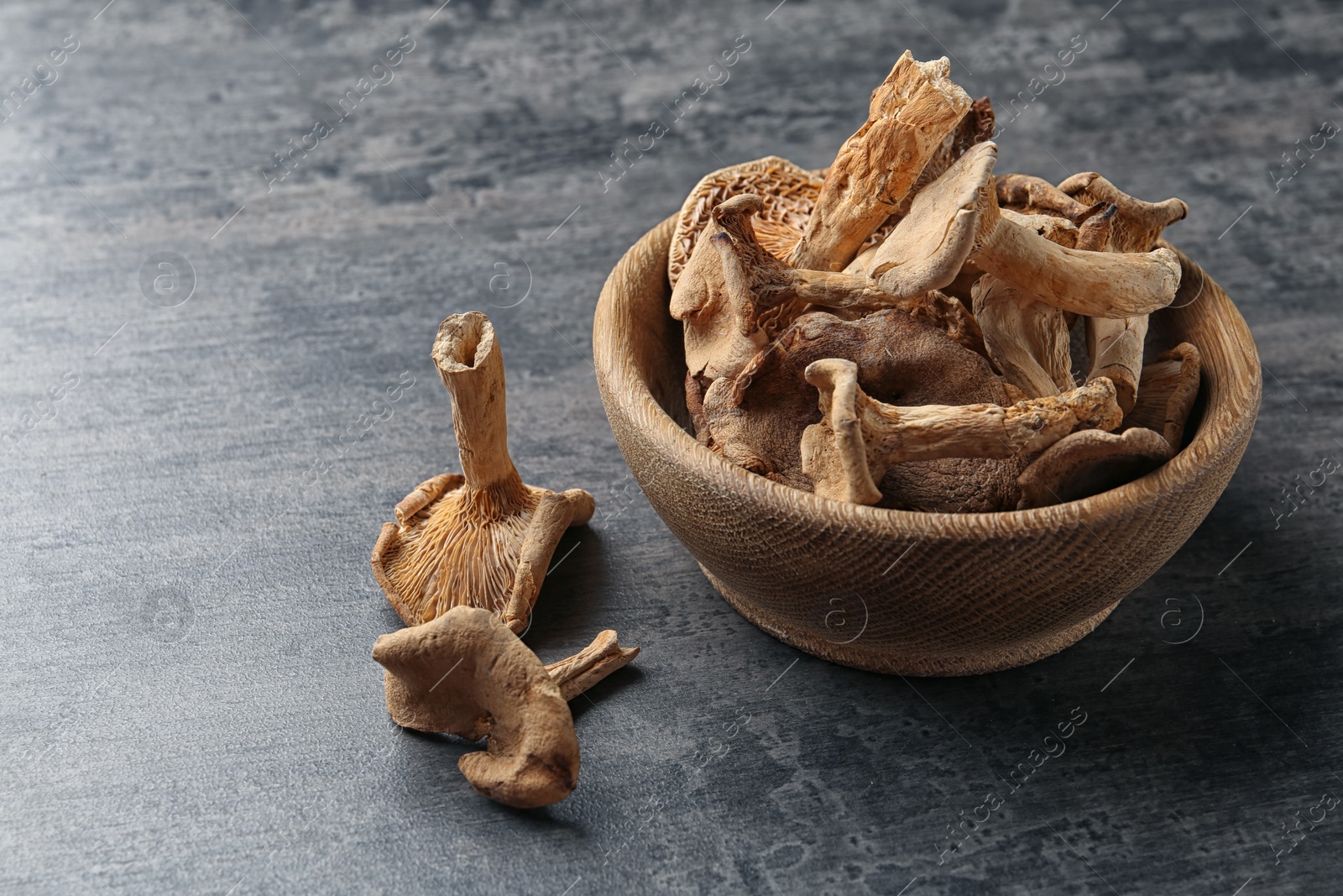 Photo of Bowl of dried mushrooms on color background