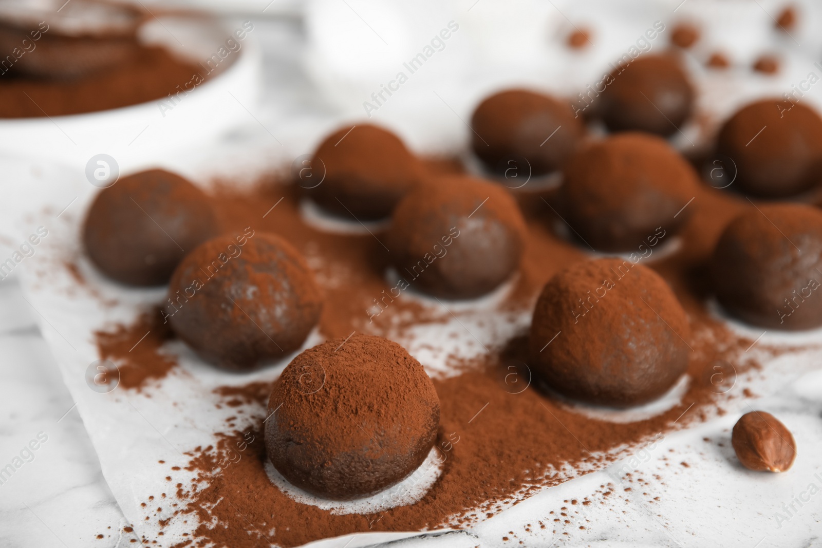 Photo of Delicious chocolate truffles powdered with cocoa on white table, closeup