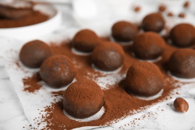 Photo of Delicious chocolate truffles powdered with cocoa on white table, closeup