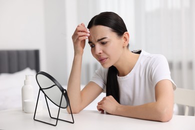 Photo of Woman with dry skin looking at mirror indoors