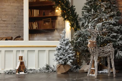 Photo of Beautiful Christmas trees, deer and other festive decor indoors, space for text. Interior design