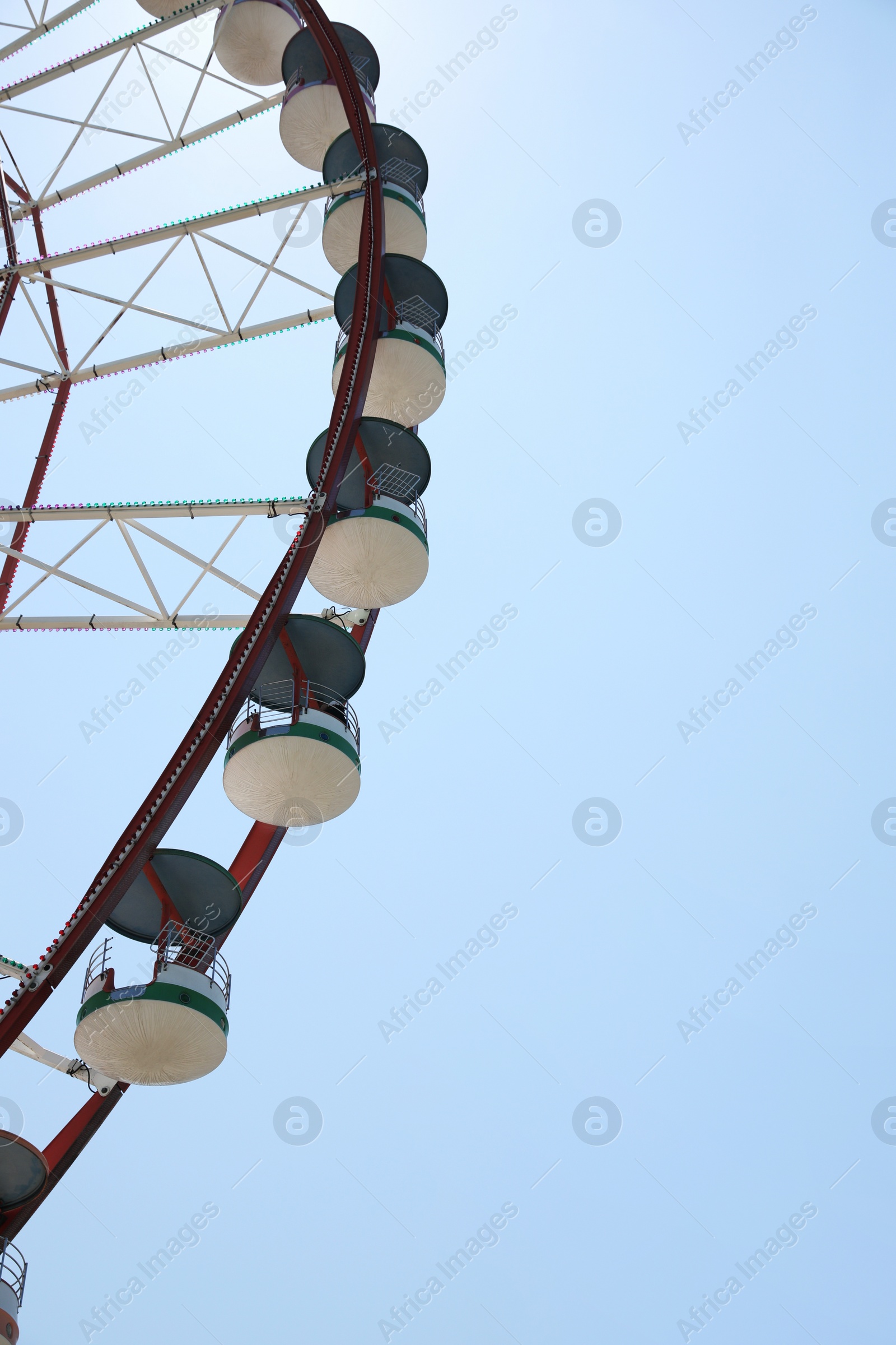 Photo of Beautiful large Ferris wheel and palm tree against blue sky, low angle view