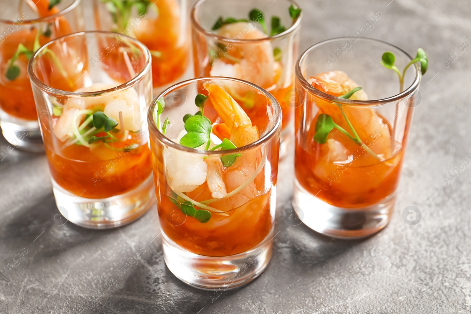 Photo of Delicious shrimp cocktail shots on grey table