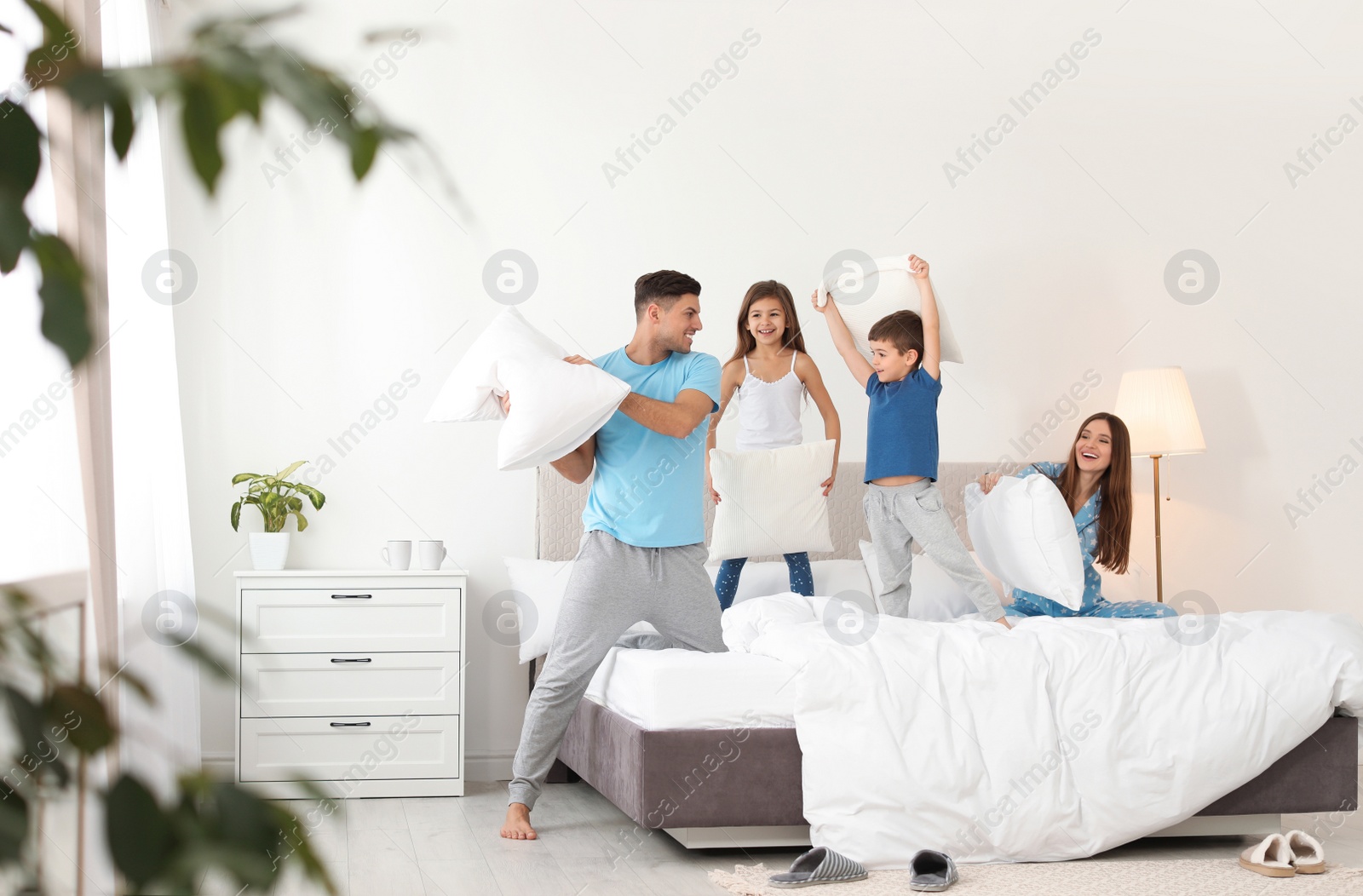 Photo of Happy family having pillow fight in bedroom