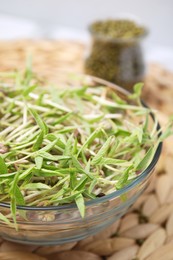 Mung bean sprouts in glass bowl on wicker mat, closeup