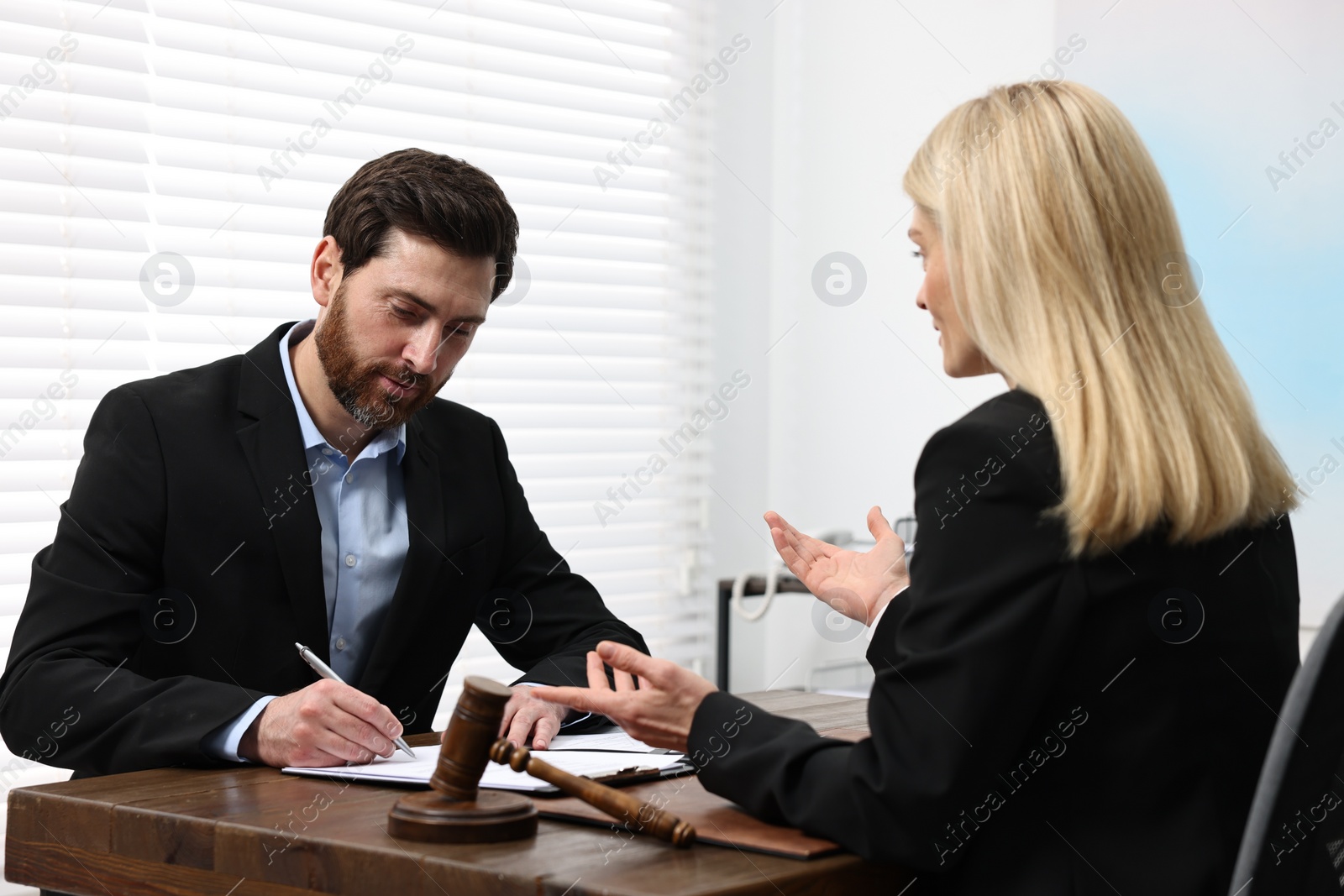 Photo of Man signing document at table in lawyer's office