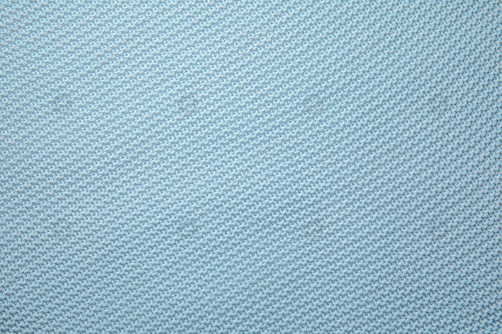 Photo of Soft light blue knitted plaid as background, top view