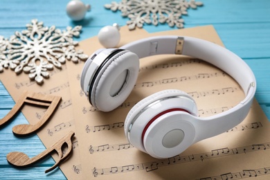 Christmas decorations, headphones and music sheets on blue wooden table, closeup