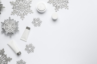 Photo of Composition with cosmetic products and snowflakes on white background, top view. Winter skin care