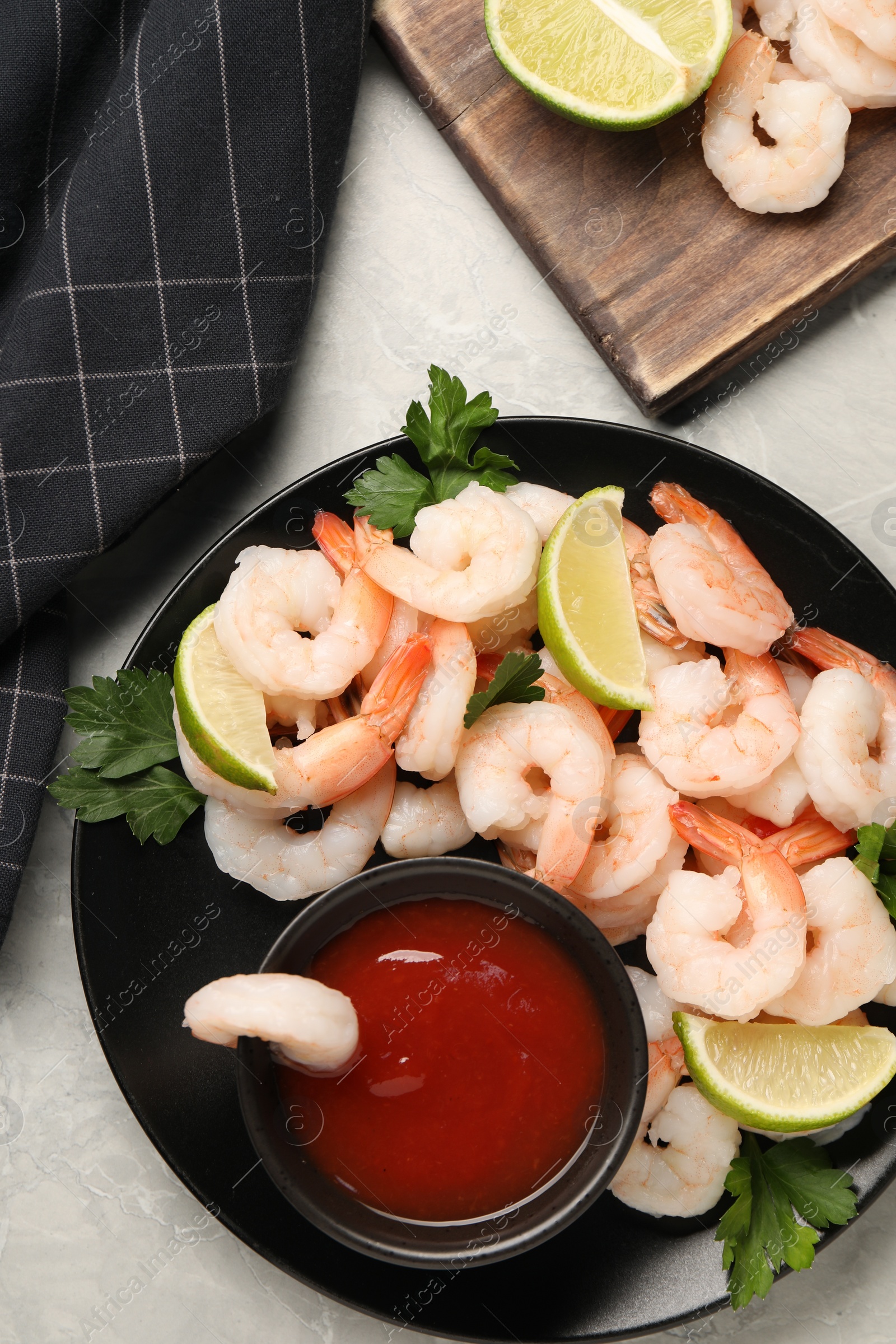 Photo of Tasty boiled shrimps with cocktail sauce, parsley and lime on light grey table, flat lay