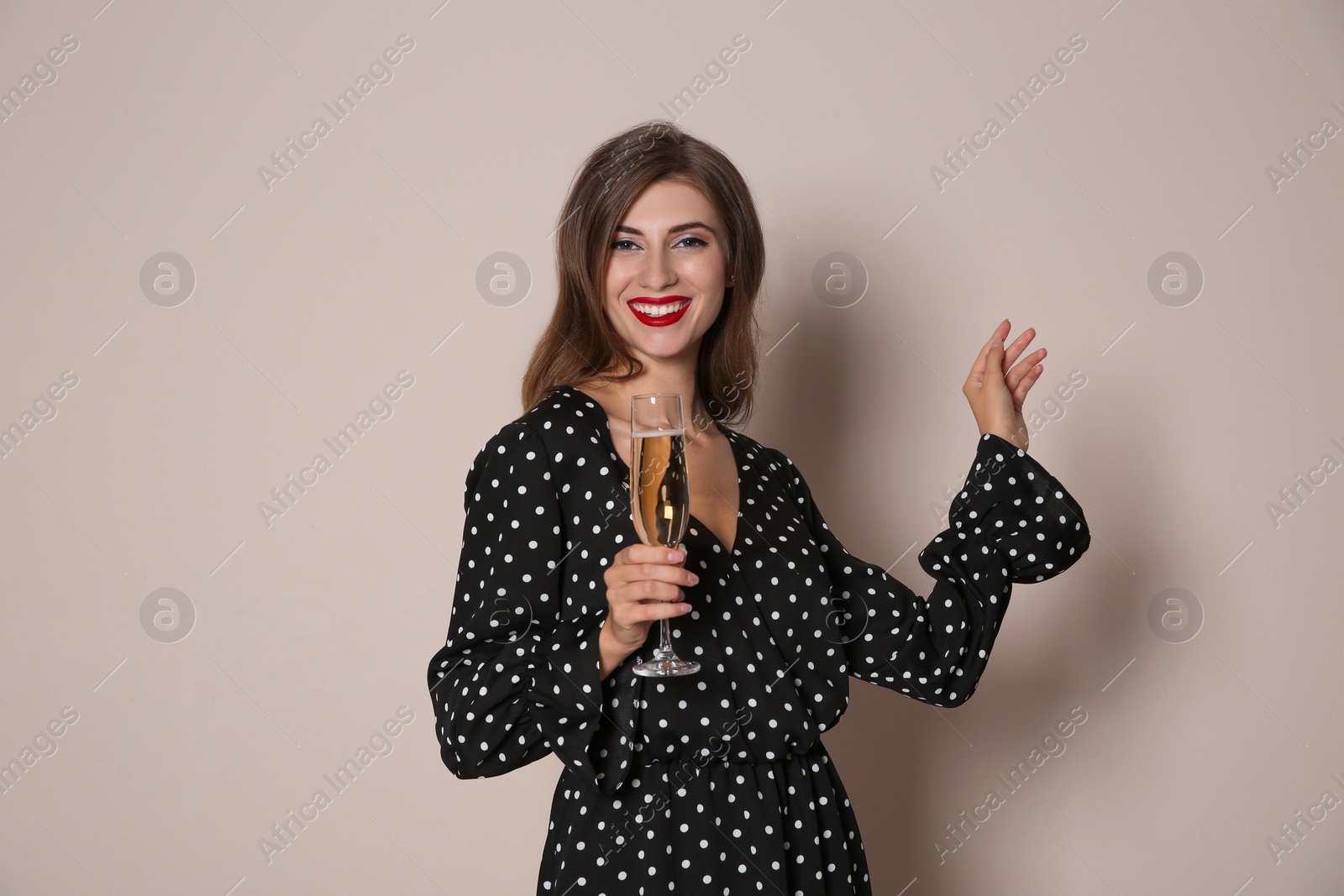 Photo of Happy woman with champagne on beige background. Christmas party