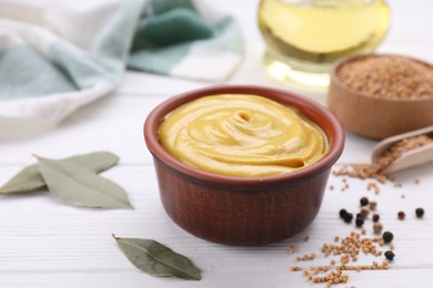 Photo of Bowl with delicious mustard and seeds on white wooden table