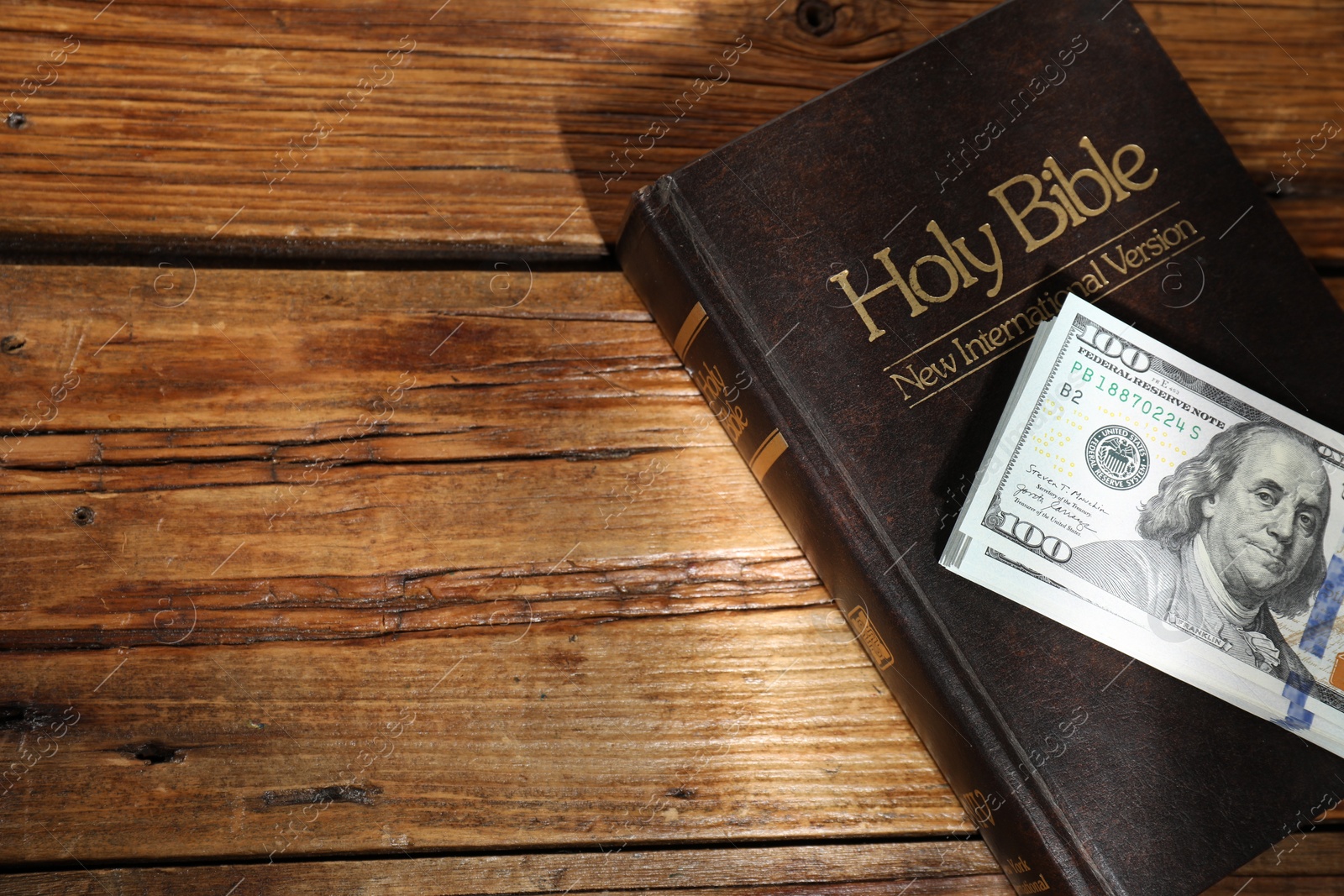 Photo of Holy Bible and money on wooden table, space for text