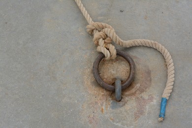 Metal ring with rope for mooring boats and yachts on stone surface, above view
