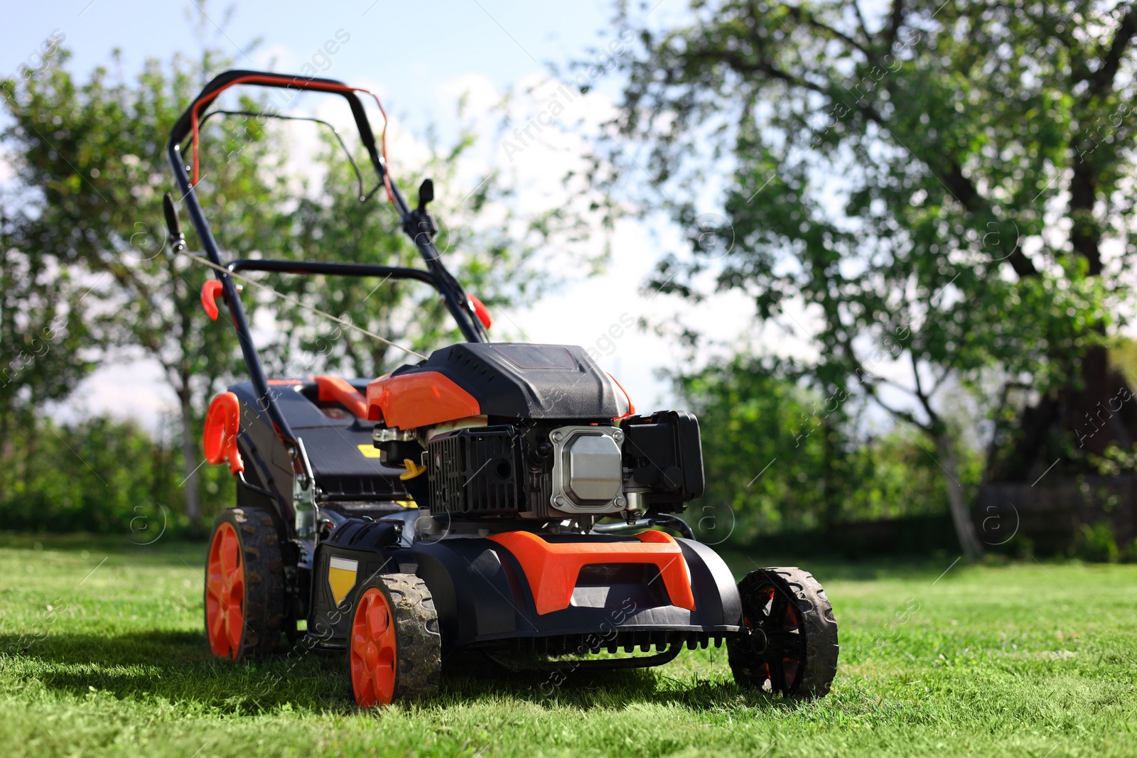 Photo of Modern lawn mower on green grass in garden