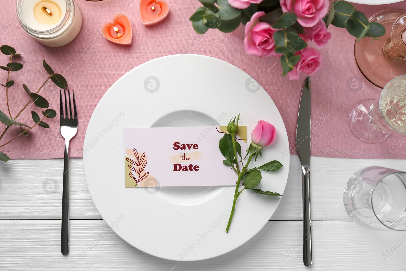 Photo of Romantic place setting with flowers and candles on white wooden table, flat lay