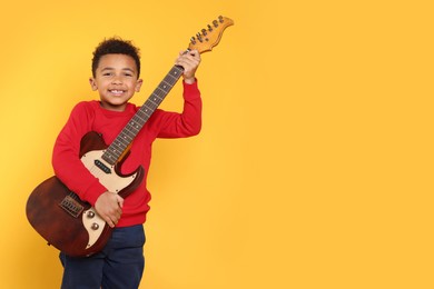 Photo of African-American boy with electric guitar on yellow background. Space for text