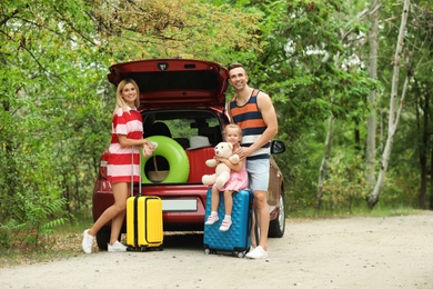 Photo of Happy family near car trunk with suitcases outdoors. Space for text