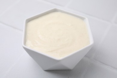 Photo of Bowl of delicious semolina pudding on white table, closeup