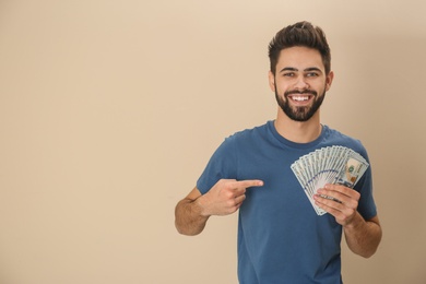 Photo of Portrait of happy young man with money on color background. Space for text
