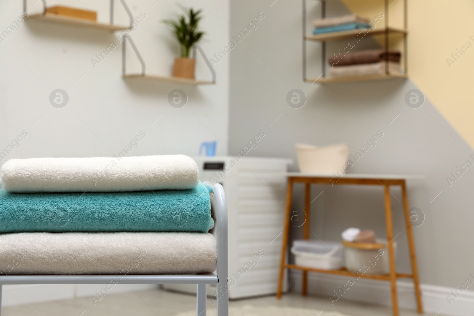 Photo of Stack of clean towels on table in laundry room. Space for text