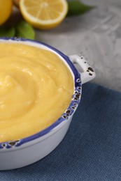 Photo of Delicious lemon curd in bowl on grey table, closeup