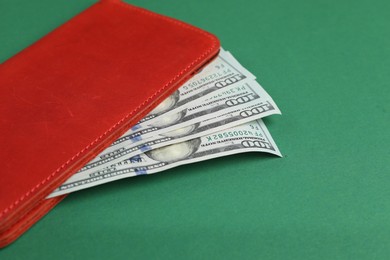 Money exchange. Wallet with dollar banknotes on green background, closeup