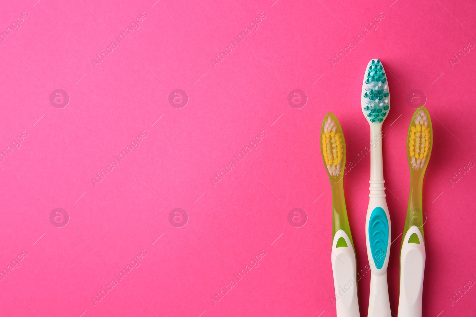 Photo of Toothbrushes on pink background, flat lay. Space for text