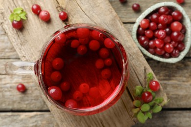 Photo of Delicious cranberry tea and berries on wooden table, flat lay