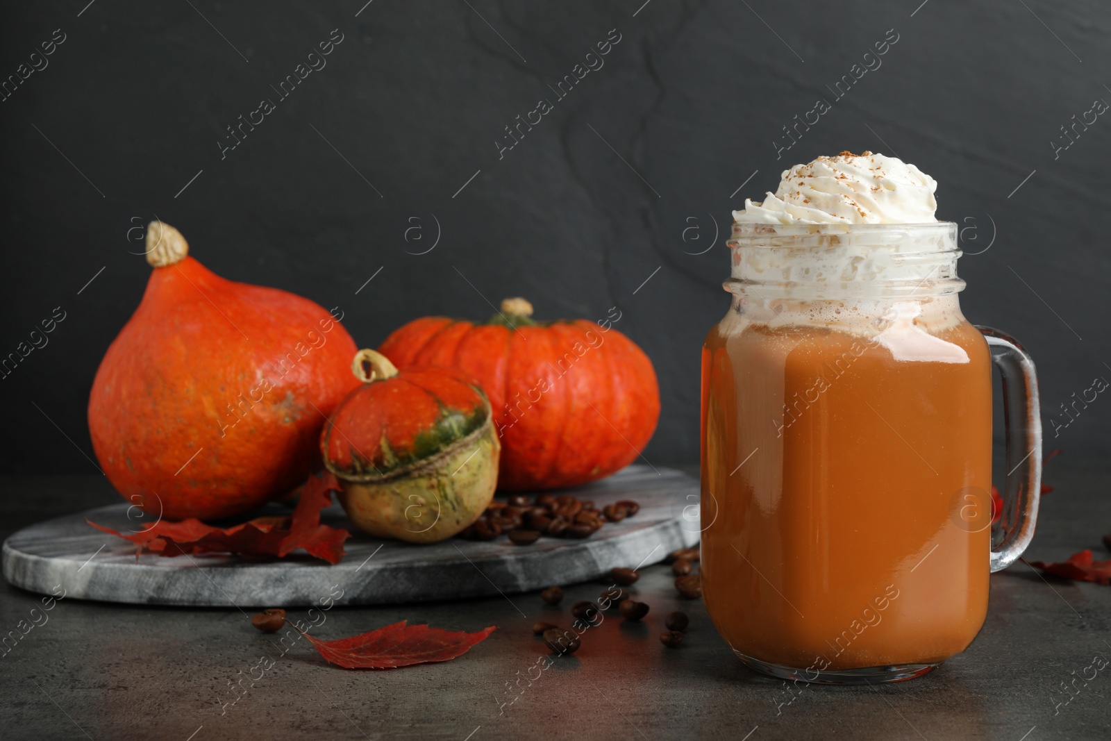 Photo of Mason jar with tasty pumpkin spice latte on grey table