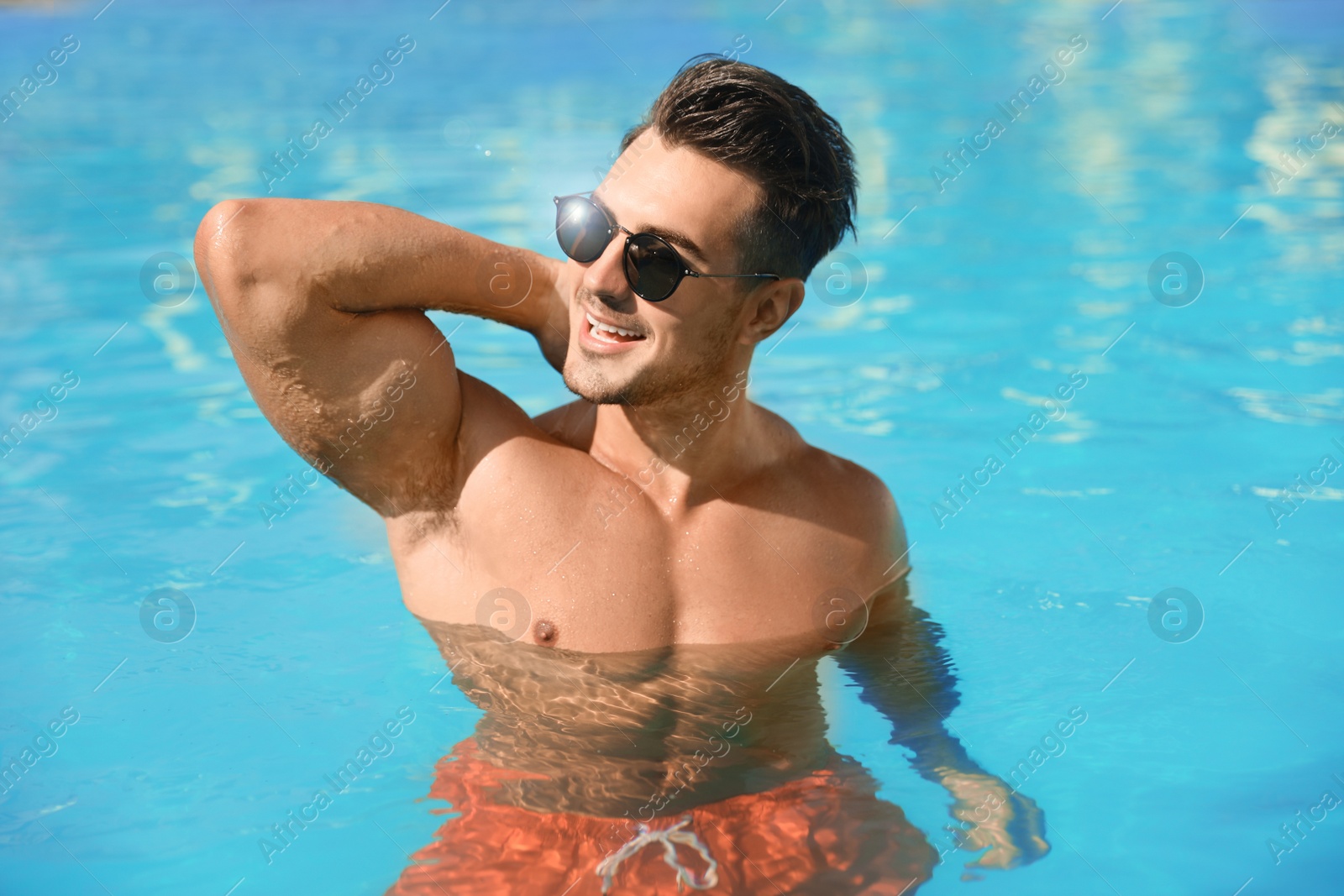 Image of Young man in pool on sunny day