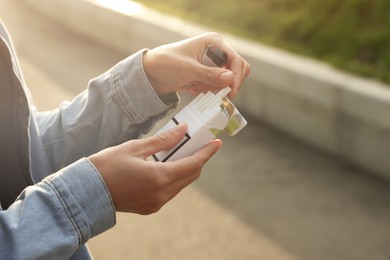 Photo of Woman taking cigarette out of pack outdoors, closeup