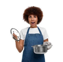 Emotional young woman in apron holding cooking pot on white background