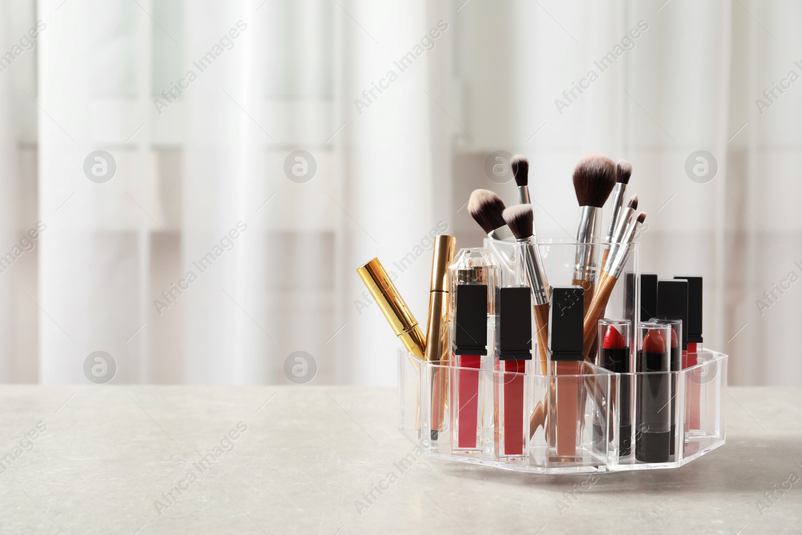 Photo of Lipstick holder with different makeup products on table indoors. Space for text