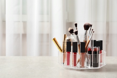 Lipstick holder with different makeup products on table indoors. Space for text