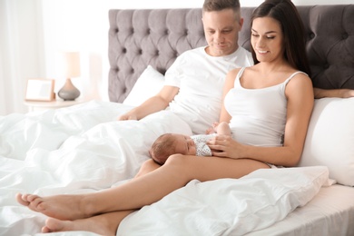 Happy couple with their newborn baby on bed