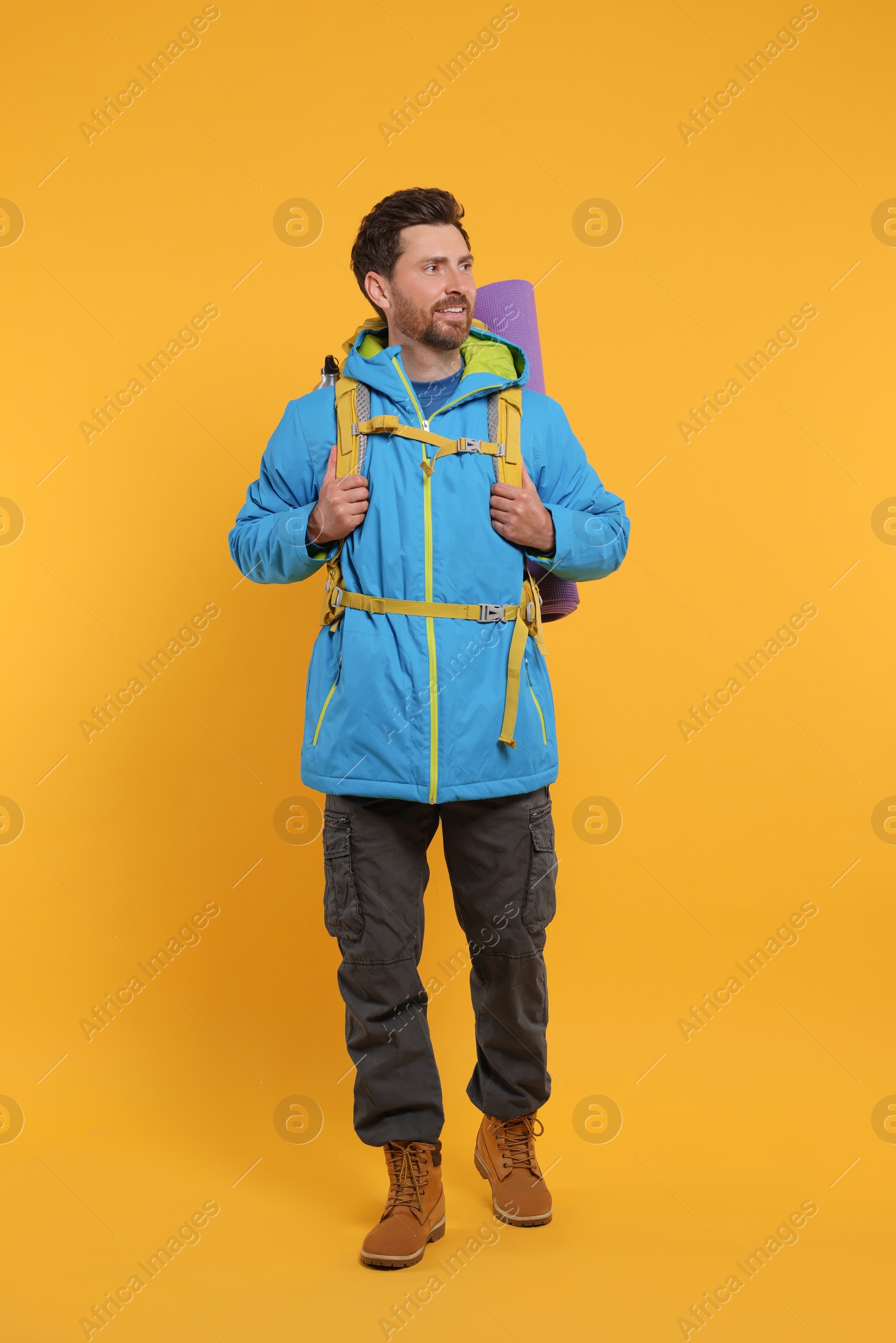 Photo of Happy man with backpack on orange background. Active tourism