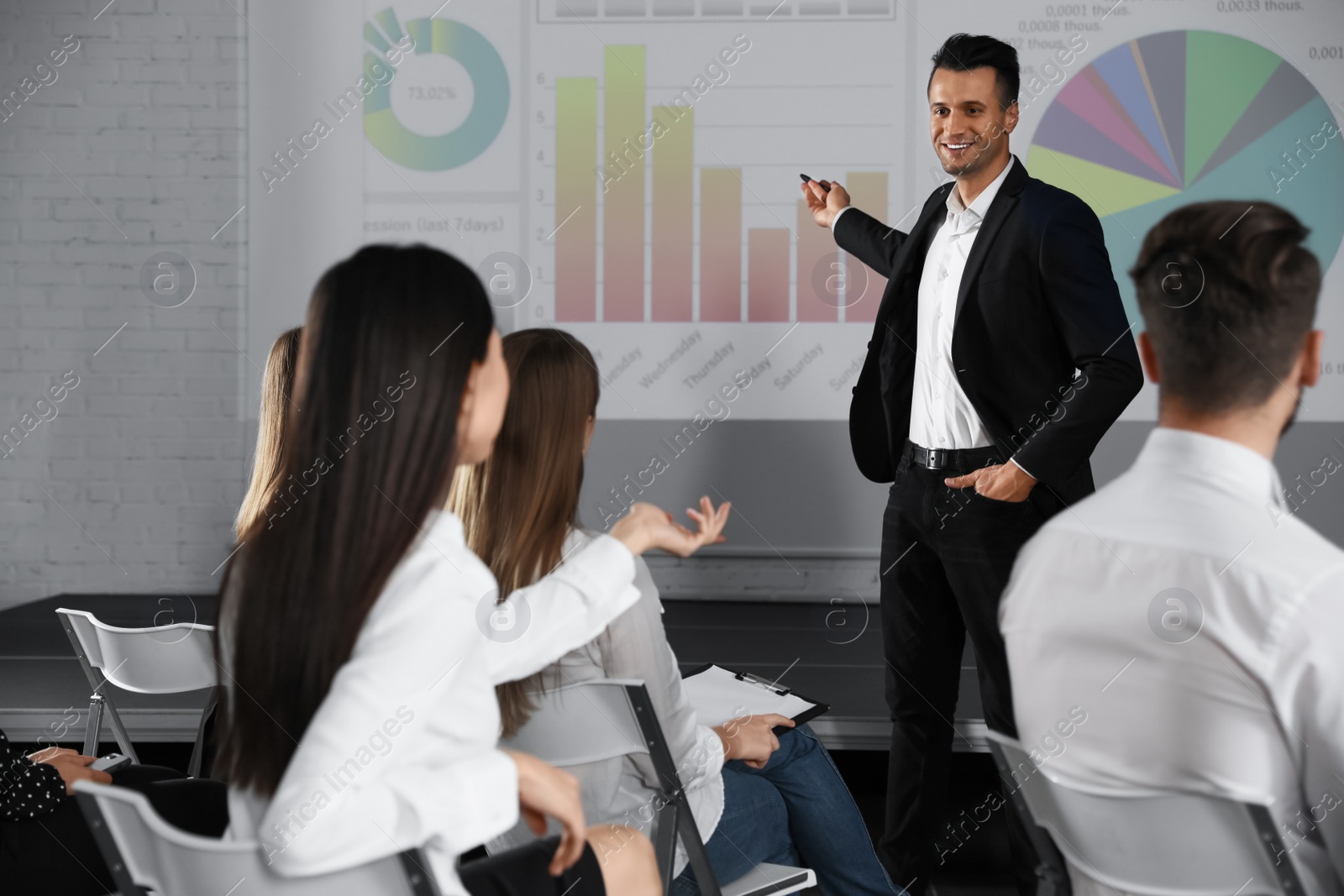 Photo of Male business trainer giving lecture in conference room with projection screen