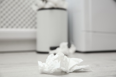 Photo of Used paper tissue on wooden floor indoors, closeup