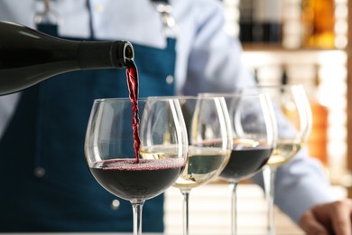 Photo of Bartender pouring wine into glass in restaurant, closeup