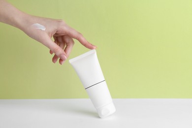 Photo of Woman with tube of cream on color background, closeup