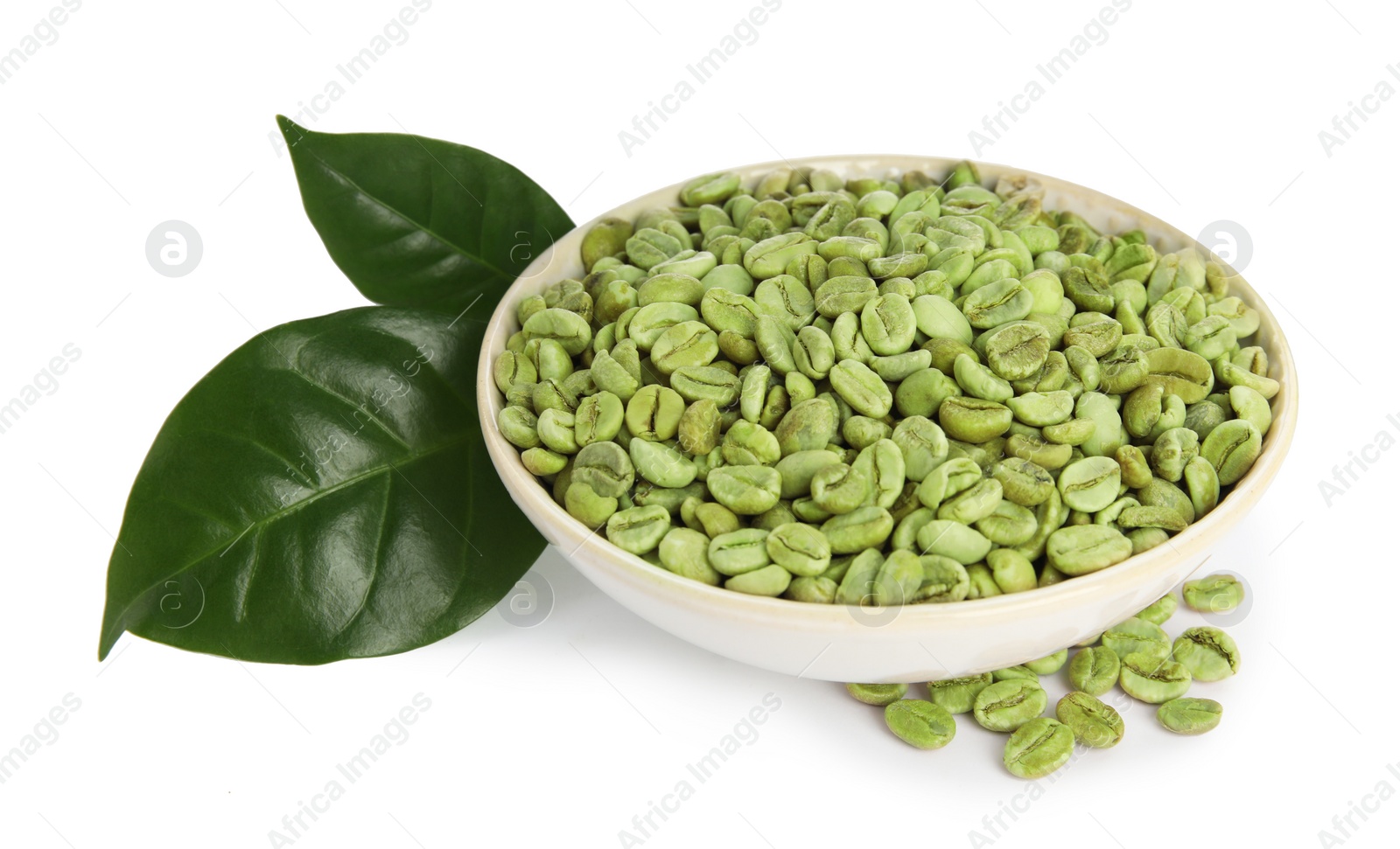 Photo of Bowl with green coffee beans and fresh leaves on white background