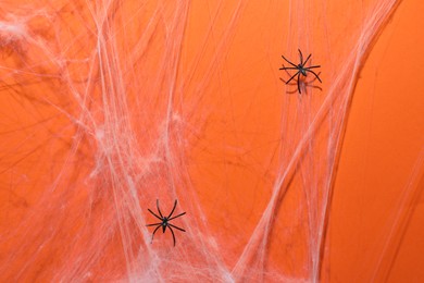 Cobweb and spiders on orange background, top view