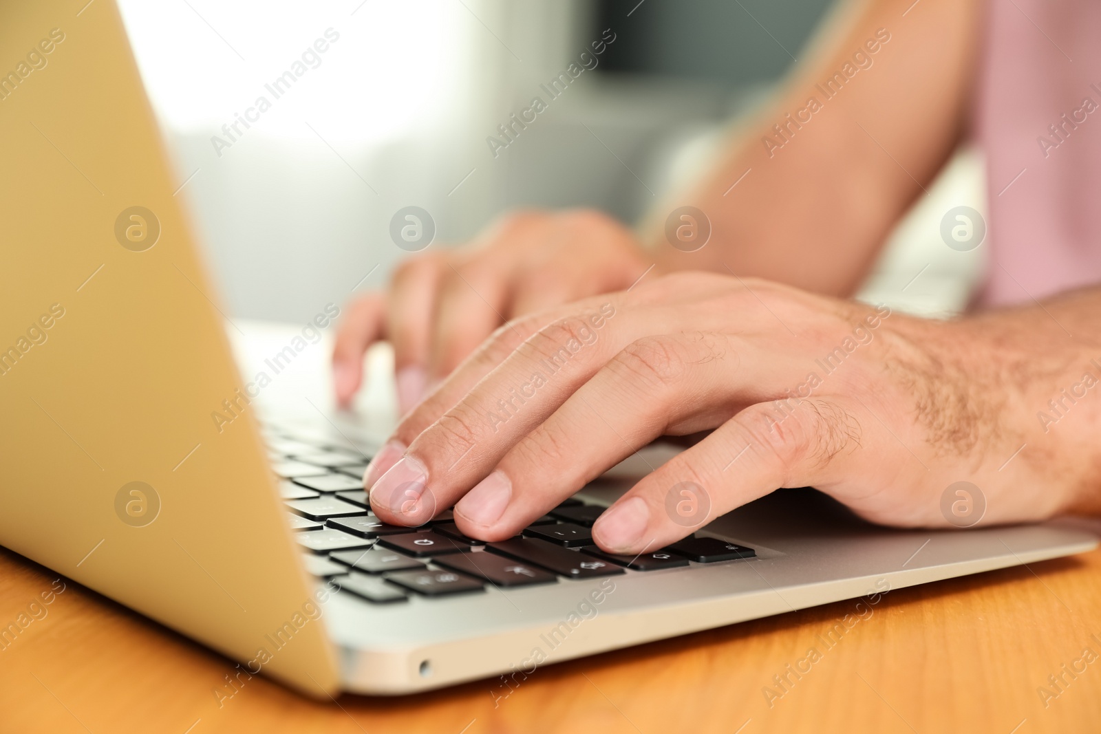 Photo of Man using laptop for search at wooden table indoors, closeup