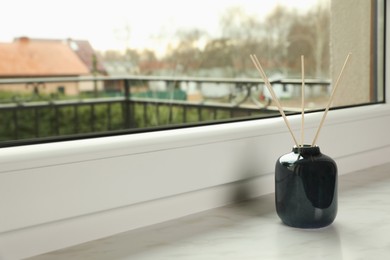 Photo of Aromatic reed air freshener on windowsill indoors, space for text