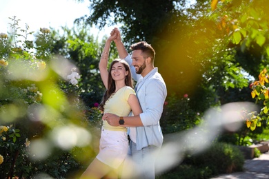 Lovely young couple dancing together in park on sunny day